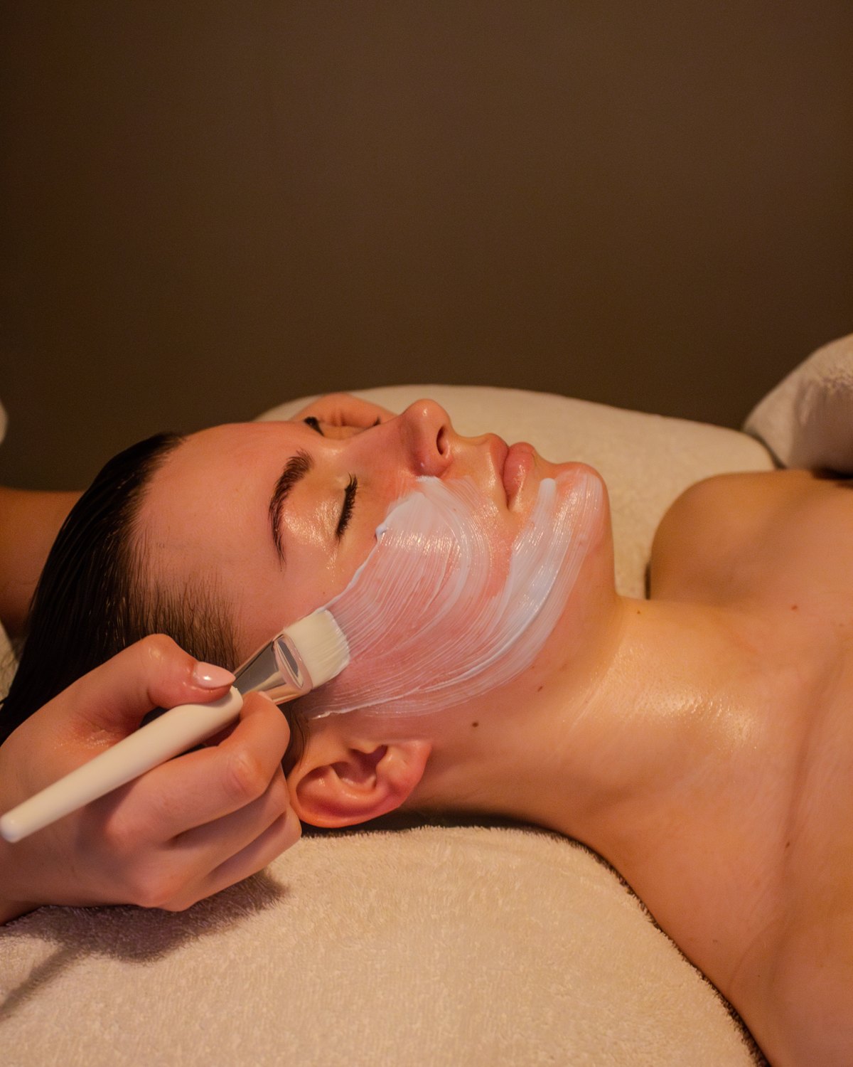 A treatment mask being brushed onto the skin